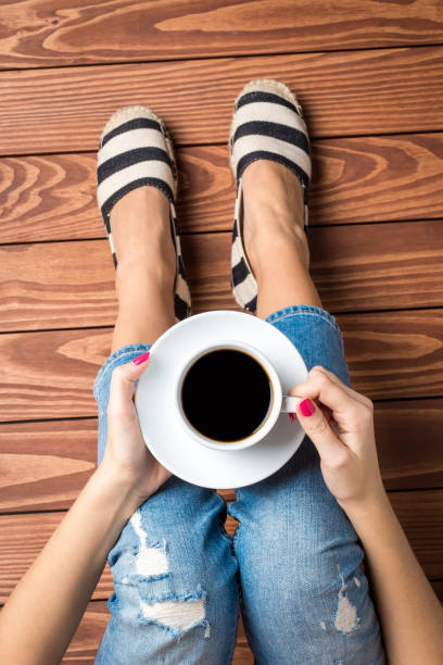 istock Woman drinking coffee while sitting on wooden floor. 817842068