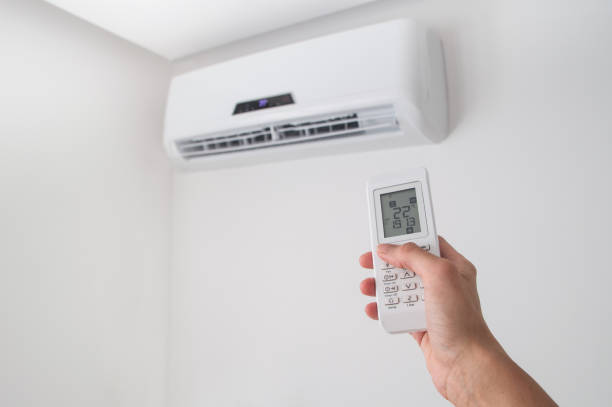 istock Hand holding remote control for air conditioner on white wall. 817846948