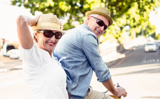 都市の自転車のために行く幸せな熟年カップルに乗る - retirement mature couple couple bicycle ストックフォトと画像