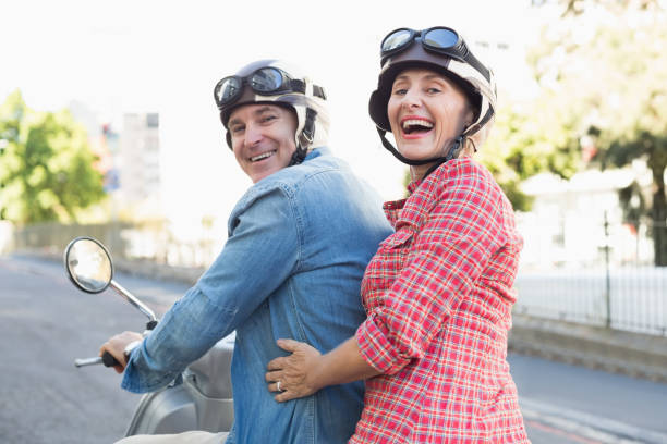 feliz pareja madura montando una moto en la ciudad - women looking over shoulder people cute fotografías e imágenes de stock