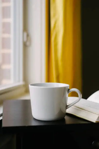 Cup and open book on nightstand.
