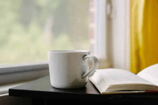 Cup and open book on nightstand.