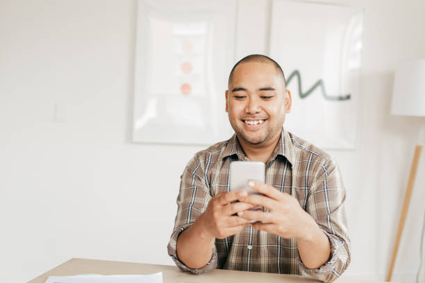 controllo della casa dal telefono cellulare - filipino ethnicity immagine foto e immagini stock