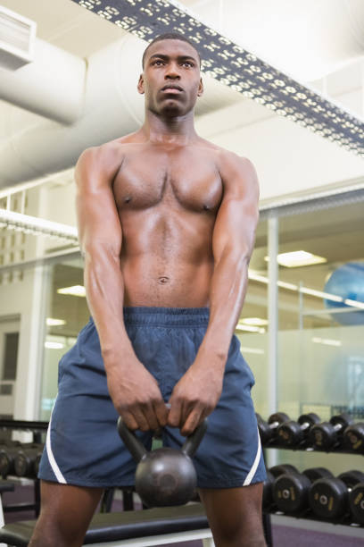 istock Shirtless muscular man lifting kettle bell in gym 818028566