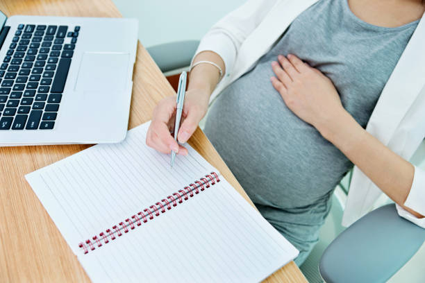 istock Pregnant woman writing in the office 818080064