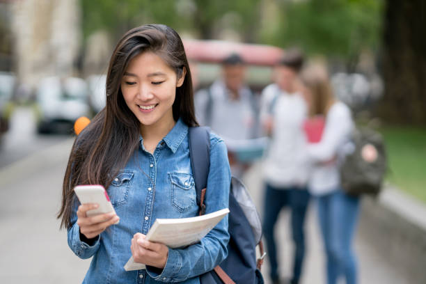 Asian female student texting on her mobile phone outdoors Portrait of an Asian female student texting on her mobile phone outdoors - lifestyle concept education student mobile phone university stock pictures, royalty-free photos & images