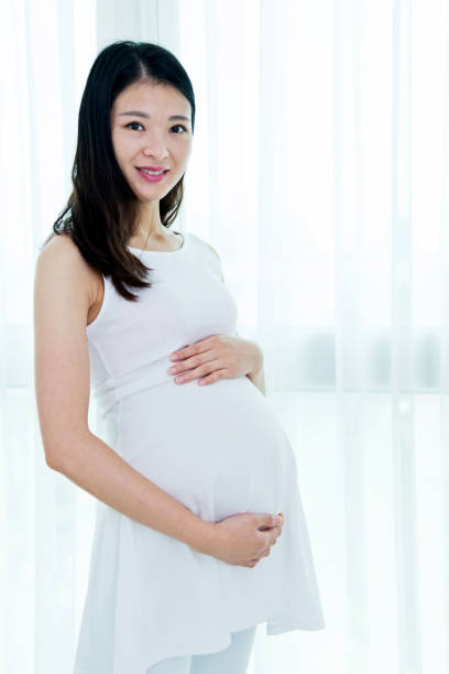 istock Pregnant woman standing at home 818106302