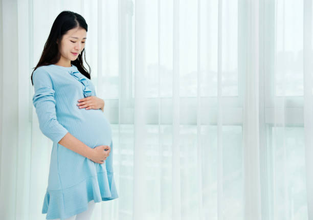 istock Pregnant woman standing at home 818108728