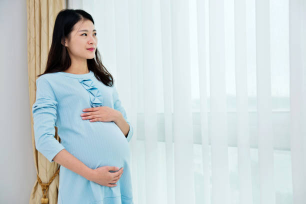 istock Pregnant woman standing at home 818111112