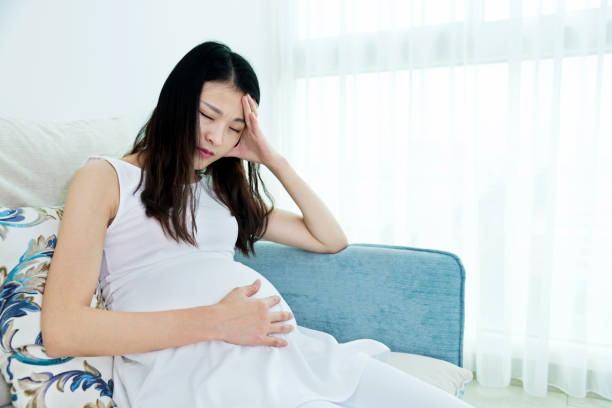 istock Pregnant woman sitting on sofa and having headache 818112380