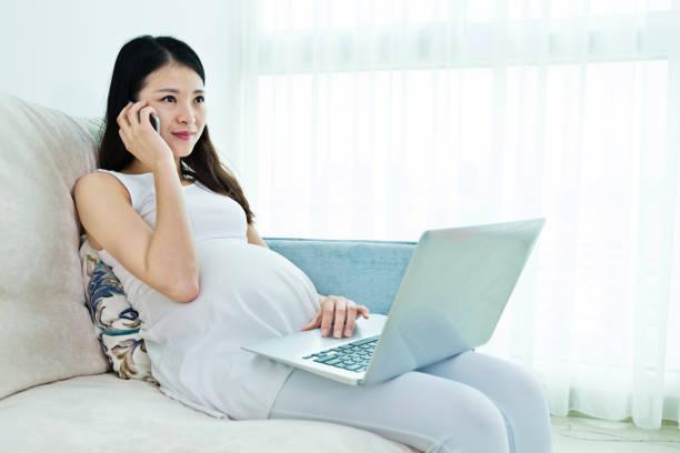 istock Pregnant women sitting on sofa and using a laptop 818112604