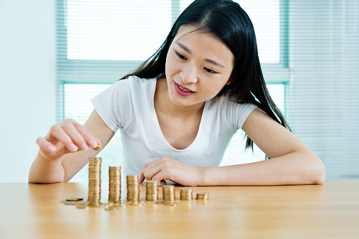 Woman putting a coin on stack of currency