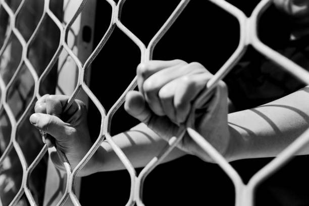 istock Close-up of woman hands on cell bars 818149502