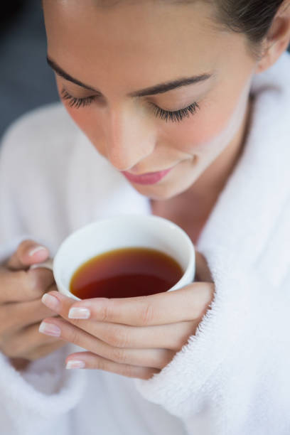 istock Beautiful woman in bathrobe having tea 818170318