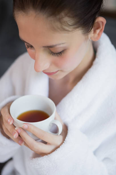 istock Beautiful woman in bathrobe having tea 818171552