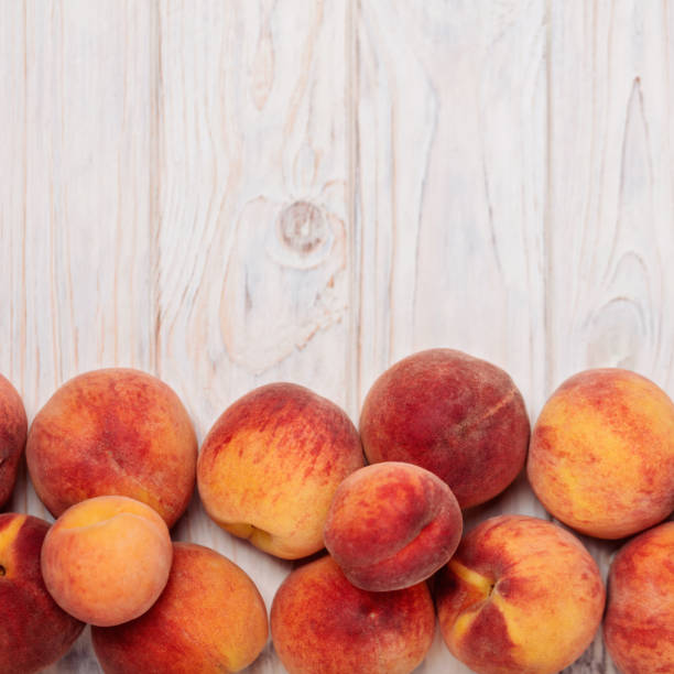 istock Ripe tasty peaches on a light wooden background. 818173404
