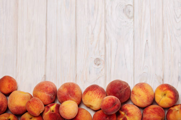 istock Ripe tasty peaches on a light wooden background. 818173632