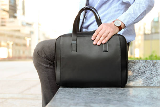 homme d’affaires assis / se reposer après une journée de travail et tenant une mallette en cuir à la main - book holding necktie businessman photos et images de collection