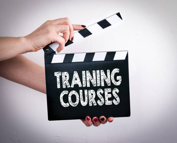 istock Training Courses. Female hands holding movie clapper 818267976