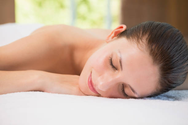 istock Beautiful woman lying on massage table at spa center 818281994