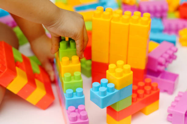 istock Child's hand building plastic toy blocks with blurred background 818282524