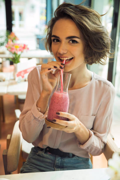 istock Beautiful young girl drinking smoothie cocktail 818283934