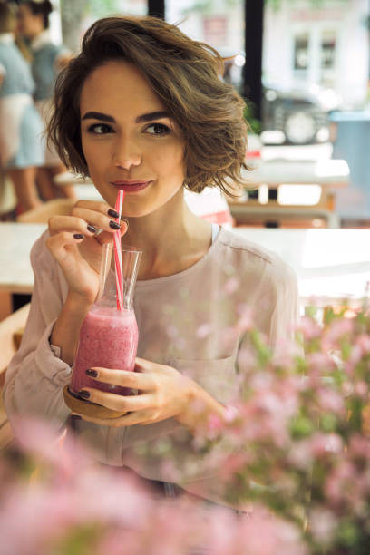 istock Pretty young woman drinking smoothie with a straw 818283954