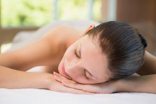 istock Beautiful woman lying on massage table at spa center 818288240