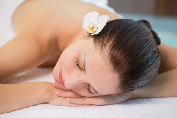 istock Beautiful woman lying on massage table at spa center 818289950