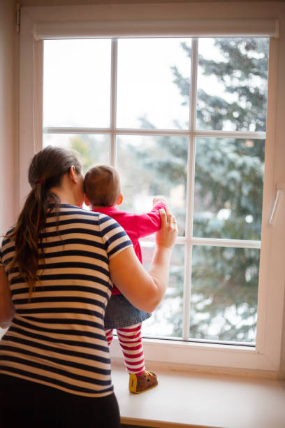 istock girl with mother looking trough the window 818291680