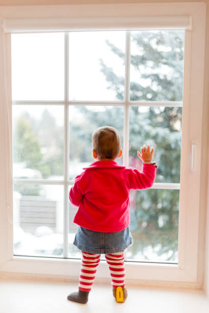 istock girl looking trough the window 818291682