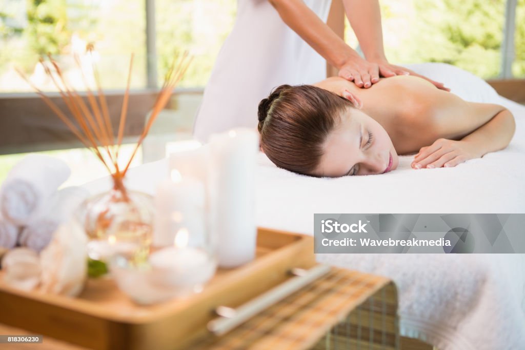 Attractive woman receiving back massage at spa center View of an attractive young woman receiving back massage at spa center Spa Stock Photo