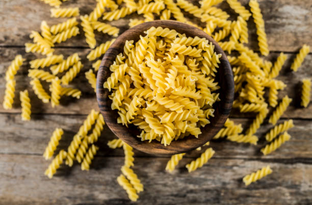 fusilli di pasta in una ciotola di legno su fondo legno per ricette salutari. - coral fungus foto e immagini stock