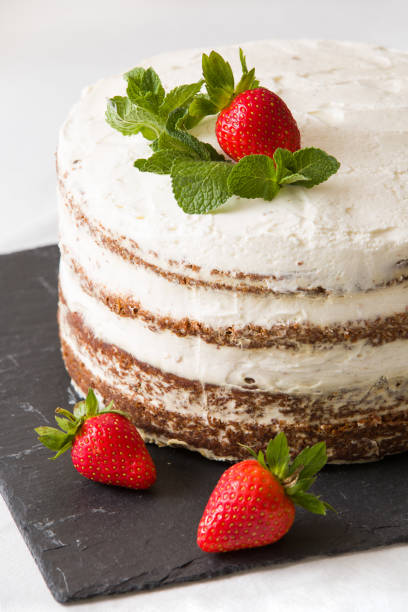 Delicious white cream icing cake with strawberry on the black board. Naked cake with cream, decorated with strawberries and mint. Delicious white cream icing cake with strawberry on the black board. Naked cake with cream, decorated with strawberries and mint. cream cake stock pictures, royalty-free photos & images