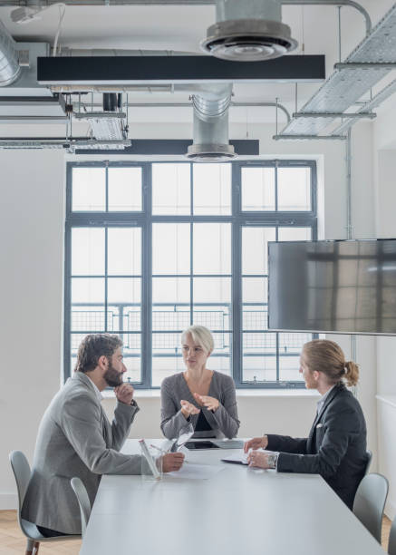 istock Serious discussion between three business people in modern office 818341442