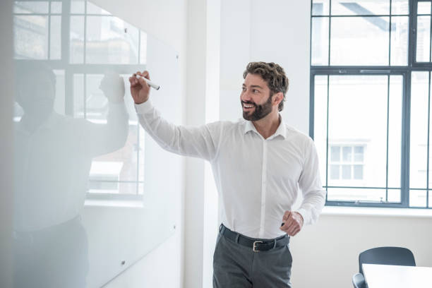 istock Mature businessman writing on whiteboard, smiling, with cheerful expression 818341468