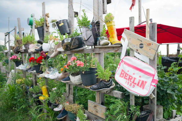 Berlin: Urban Gardening project, raise beet Berlin, Germany - July 15, 2017: flowers in shoes as a alternative raised bed in urban gardening project. Bag with Berlin-Sign in front. community garden sign stock pictures, royalty-free photos & images