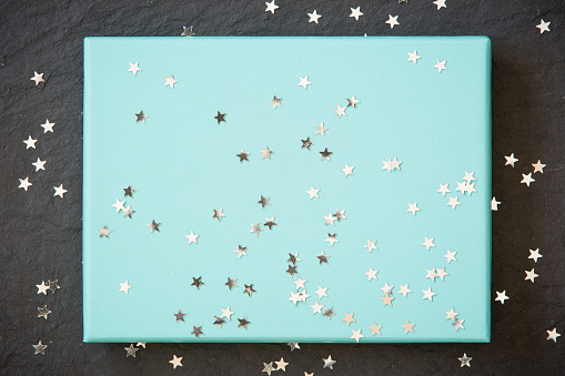 rectangular light blue box on black background with silver stars decorations. Holiday greetings. Engagement. turquoise on black board.
