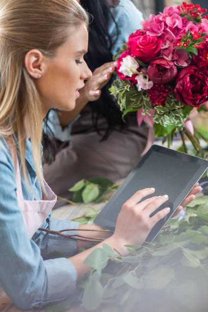 istock beautiful young blonde woman using digital tablet with blank screen while working in flower shop 818380652