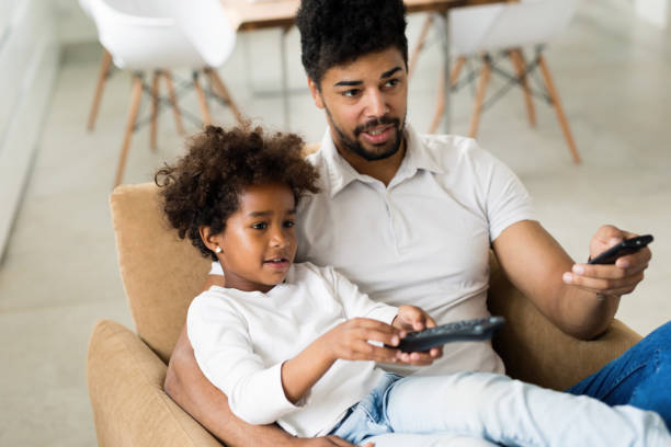 istock Father and daughter sitting on couch at home 818389860