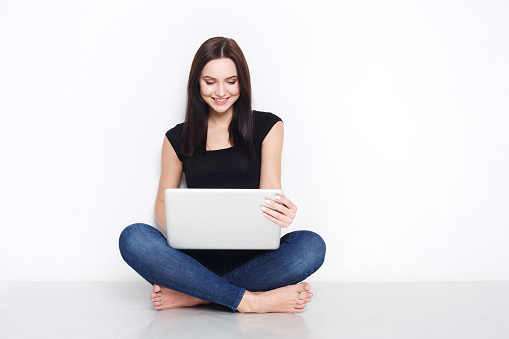 Freelance or work at home laptop. Beautiful woman in casual sit on floor and work with portable computer with crossed legs