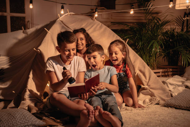 istock multicultural group of excited children with lighter reading book at home 818444334