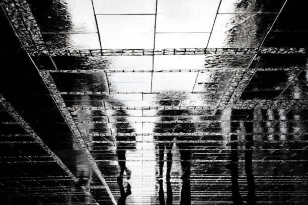 istock Blurry people reflection shadow on rainy city street 818445176