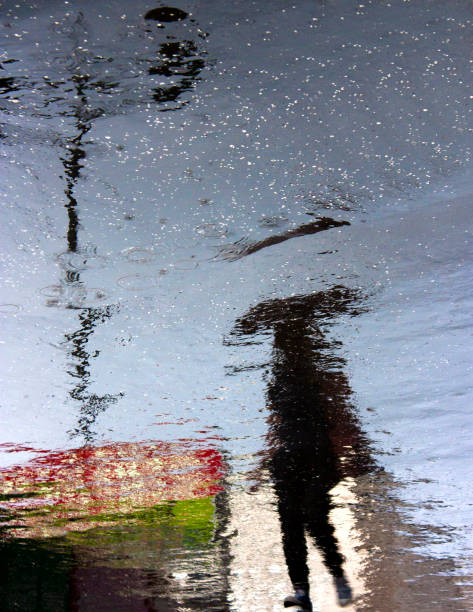 istock Blurry person reflection shadow on rainy city street 818446326