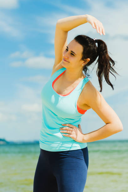 istock attractive young girl practicing physical exercises on a beach in the summer 818474234