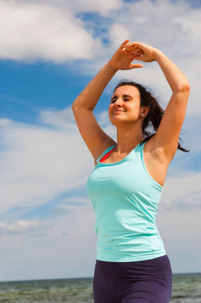 istock attractive young girl practicing physical exercises on a beach in the summer 818476770