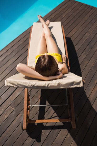 istock Beautiful woman in bikini relaxing by pool 818479174