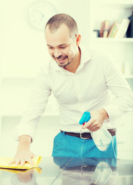 istock Positive young man cleaning office desk 818498582