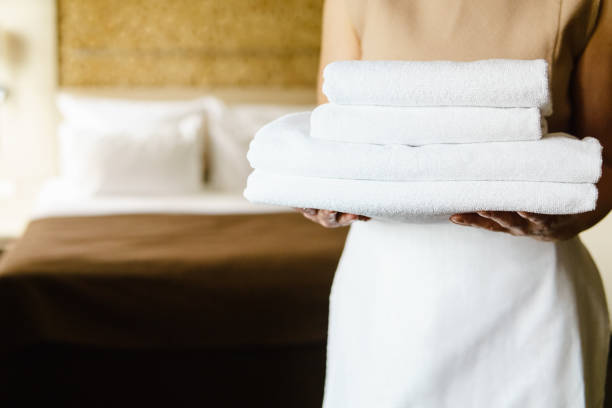 istock Maid holds clean towels while standing in the hotel room. 818560908
