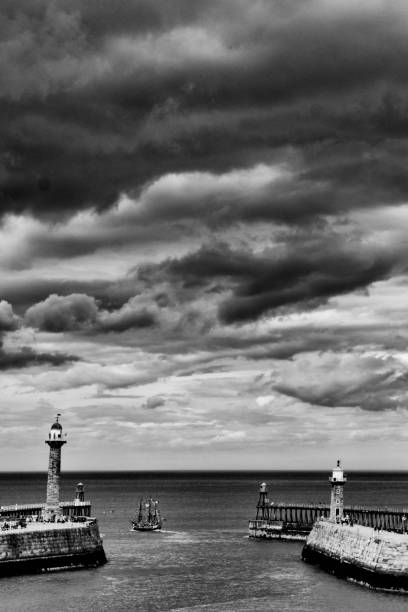 The harbour wall at Whitby with the two piers and sail boat leaving harbour.